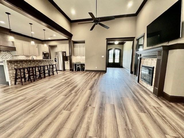 unfurnished living room featuring crown molding, a towering ceiling, light hardwood / wood-style flooring, and ceiling fan