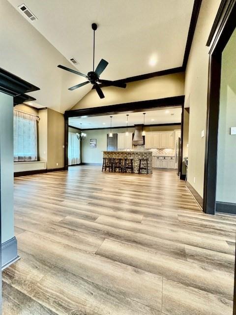 unfurnished living room with ceiling fan, vaulted ceiling, and light hardwood / wood-style floors