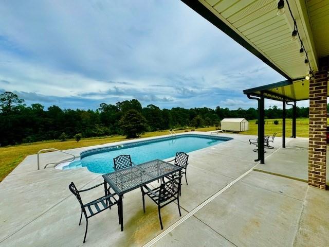 view of swimming pool featuring a storage shed and a patio area