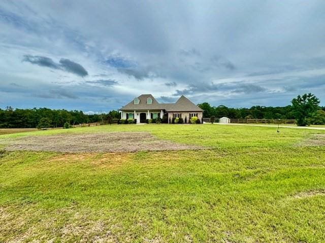 view of front of home with a rural view and a front yard