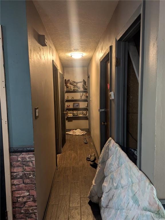 corridor with a textured ceiling and hardwood / wood-style floors