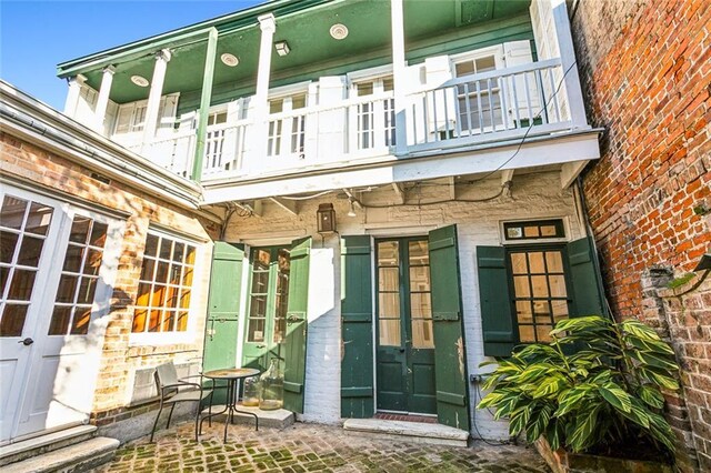 rear view of property with a balcony, french doors, and a patio