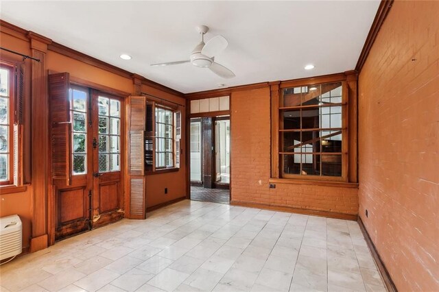 spare room with brick wall, ornamental molding, french doors, and ceiling fan