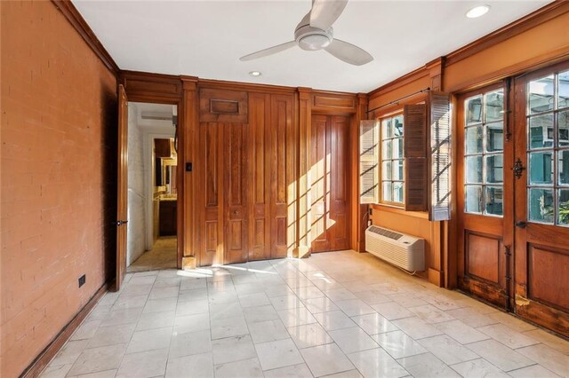 empty room with a wall unit AC, ceiling fan, brick wall, and crown molding