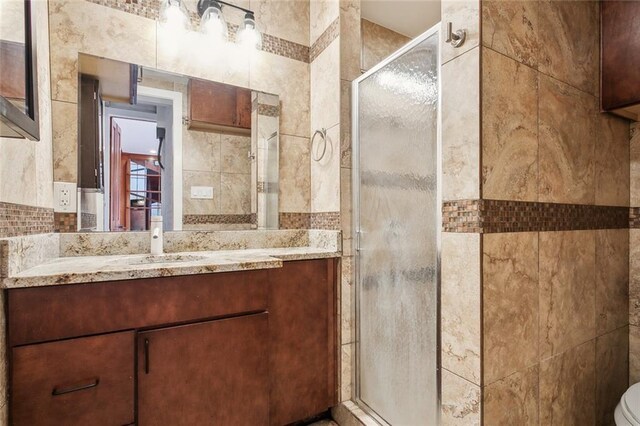 bathroom featuring tile walls, walk in shower, and vanity