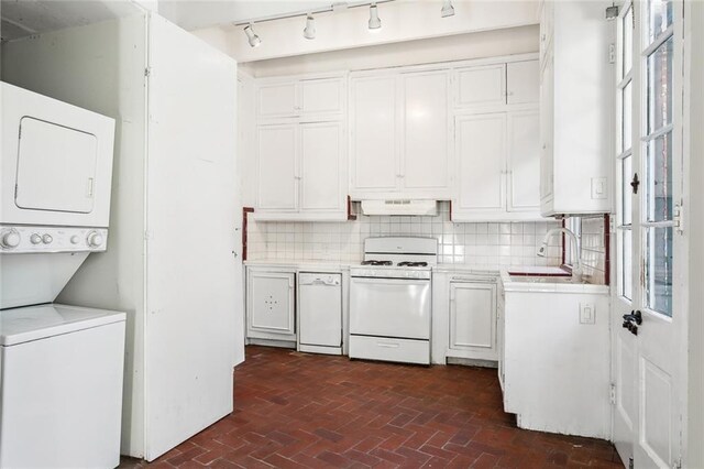 laundry room with sink, stacked washing maching and dryer, and a healthy amount of sunlight