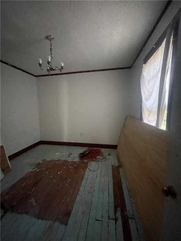 unfurnished room featuring hardwood / wood-style flooring, a chandelier, and a textured ceiling