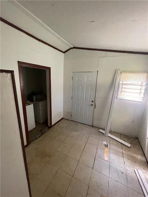 foyer entrance featuring washing machine and dryer, vaulted ceiling, and ornamental molding