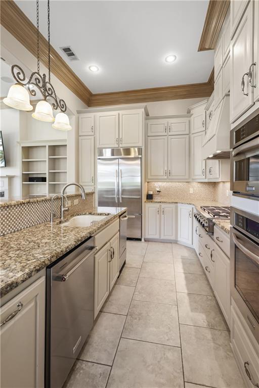 kitchen featuring light stone countertops, appliances with stainless steel finishes, white cabinets, and decorative backsplash