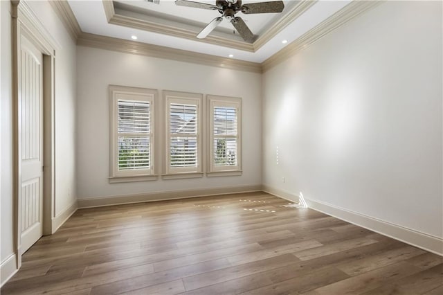 unfurnished room featuring hardwood / wood-style flooring, ornamental molding, a raised ceiling, and ceiling fan