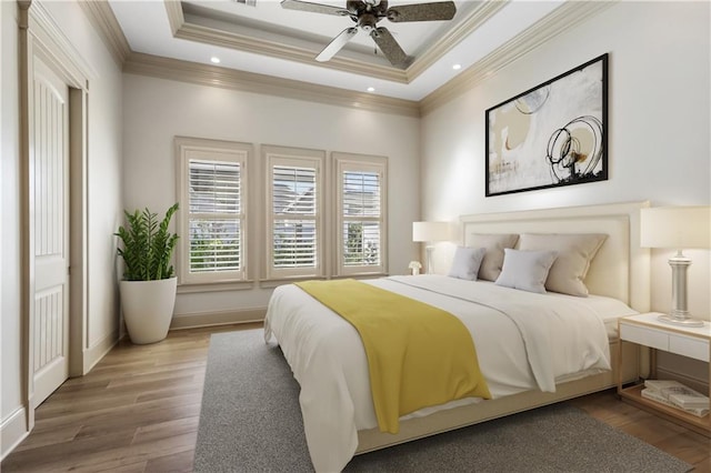 bedroom with a raised ceiling, wood-type flooring, ornamental molding, and ceiling fan