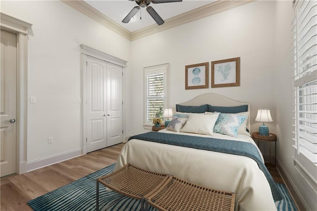 bedroom featuring hardwood / wood-style flooring, ornamental molding, ceiling fan, and a closet