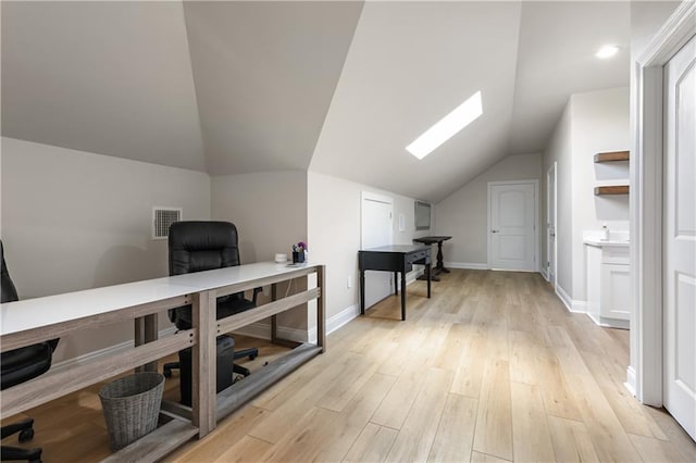 office area with light hardwood / wood-style flooring and vaulted ceiling with skylight