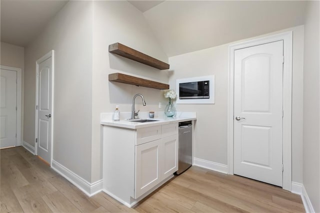 kitchen featuring white cabinetry, sink, black microwave, and light hardwood / wood-style flooring