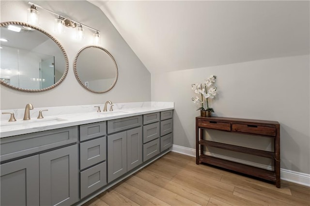 bathroom with hardwood / wood-style flooring, vaulted ceiling, and vanity