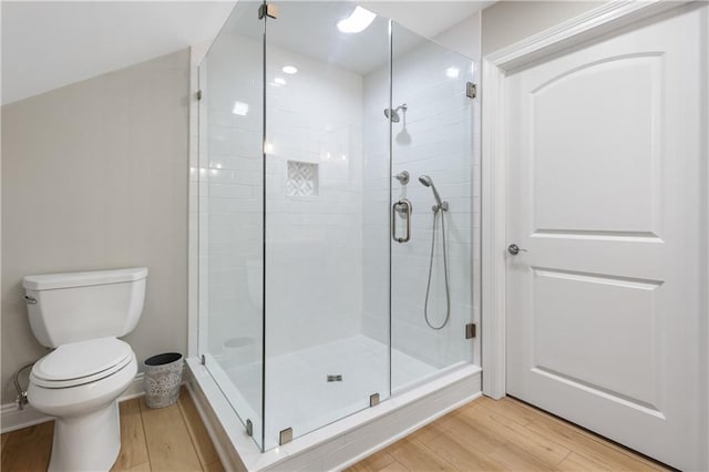 bathroom featuring hardwood / wood-style flooring, a shower with door, and toilet