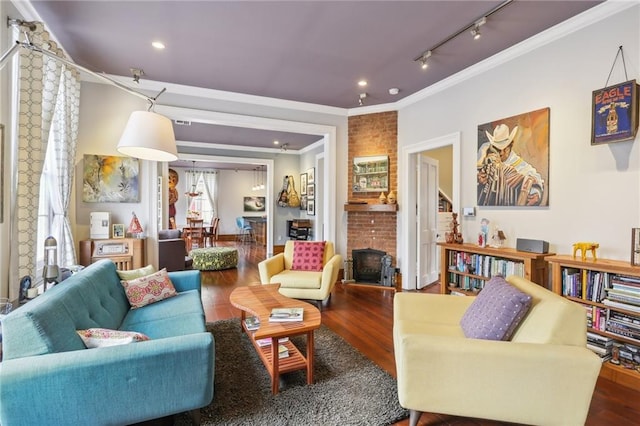 living room featuring track lighting, wood-type flooring, a large fireplace, and ornamental molding