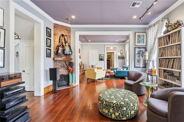 living area with ornamental molding, a large fireplace, track lighting, and dark hardwood / wood-style floors