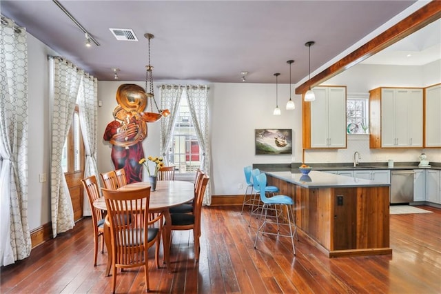 kitchen featuring dark wood-type flooring, sink, decorative light fixtures, dishwasher, and a kitchen island