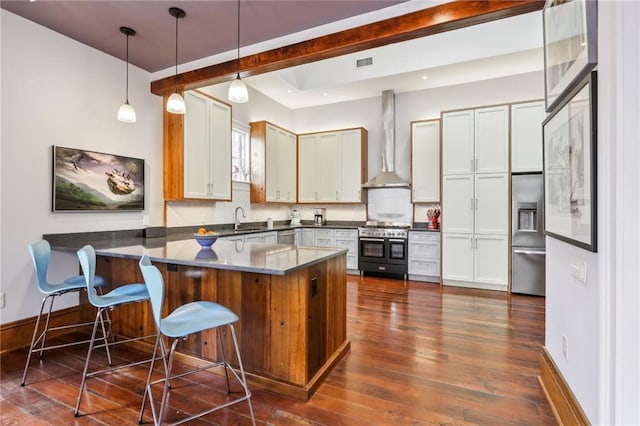 kitchen featuring sink, a breakfast bar area, white cabinetry, stainless steel appliances, and wall chimney exhaust hood