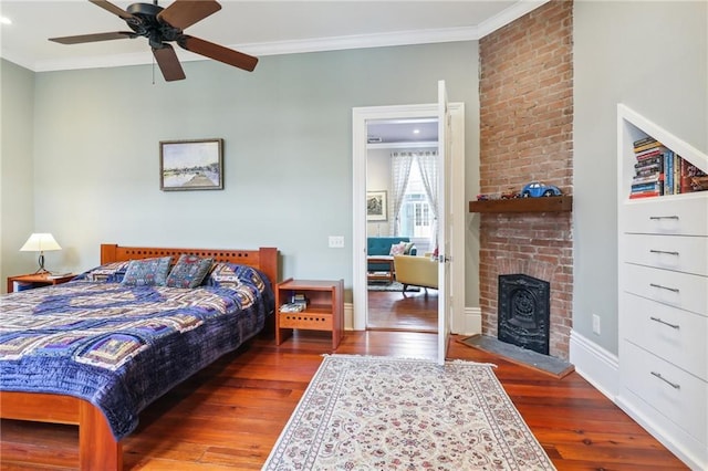 bedroom with crown molding, ceiling fan, wood-type flooring, and a brick fireplace