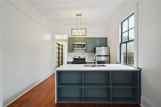 kitchen featuring sink, green cabinets, appliances with stainless steel finishes, hanging light fixtures, and dark hardwood / wood-style flooring