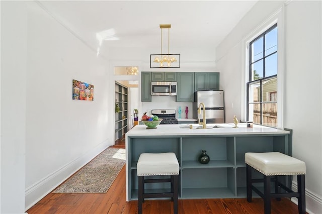 kitchen featuring a breakfast bar area, hanging light fixtures, dark hardwood / wood-style floors, green cabinets, and stainless steel appliances