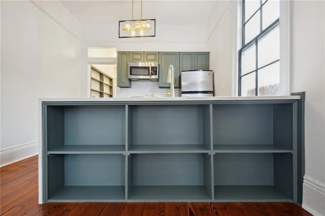 kitchen featuring dark wood-type flooring, decorative light fixtures, refrigerator, and green cabinets