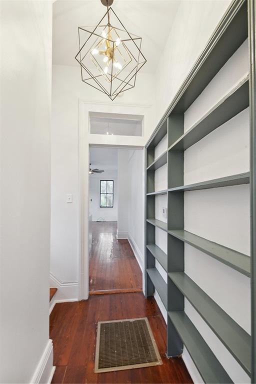 corridor with a notable chandelier and dark hardwood / wood-style flooring