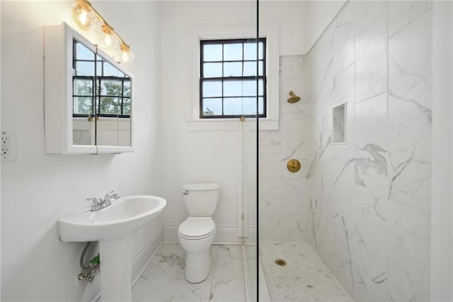 bathroom with a healthy amount of sunlight, tiled shower, sink, and toilet