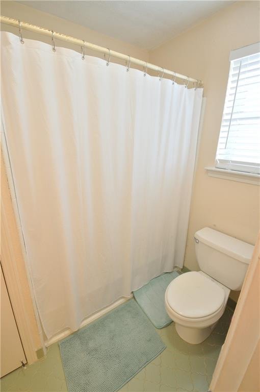 bathroom featuring walk in shower and toilet