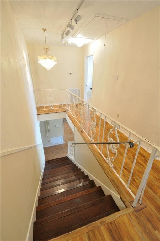 stairway featuring hardwood / wood-style flooring and track lighting