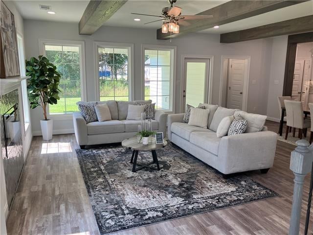 living room featuring beam ceiling, ceiling fan, a premium fireplace, and hardwood / wood-style flooring