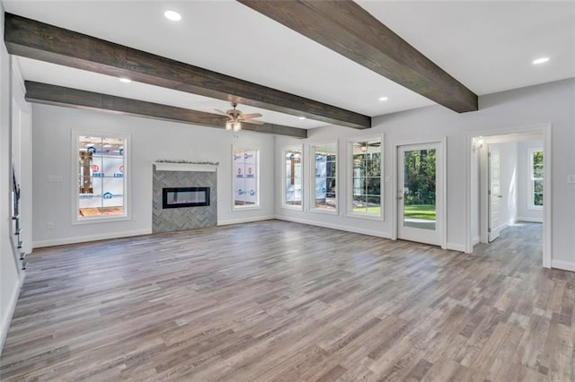 unfurnished living room with light hardwood / wood-style floors, a fireplace, beam ceiling, and ceiling fan