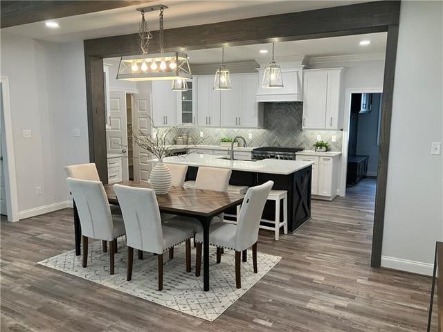 dining room featuring beamed ceiling, sink, dark hardwood / wood-style flooring, and ornamental molding