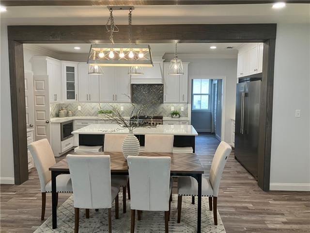 dining space featuring wood-type flooring, beamed ceiling, and crown molding