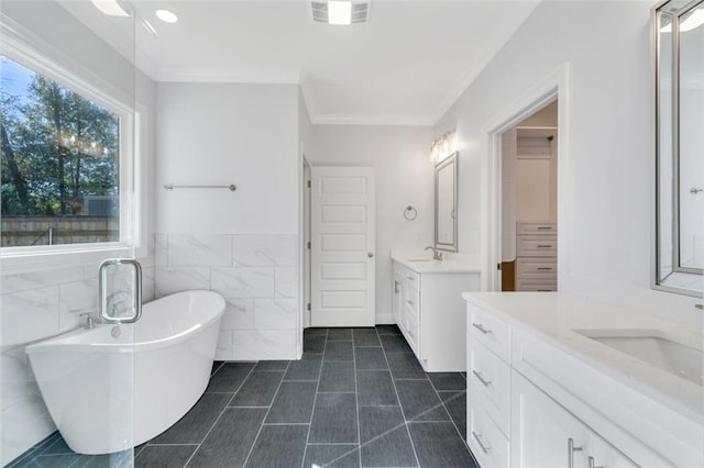 bathroom with vanity, tile walls, crown molding, and a washtub