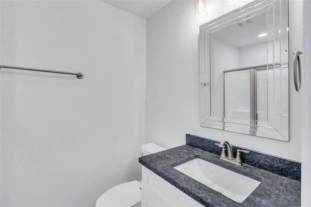 bathroom featuring an enclosed shower, vanity, and toilet