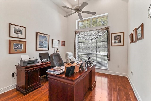 office featuring a high ceiling, ceiling fan, and dark wood-type flooring