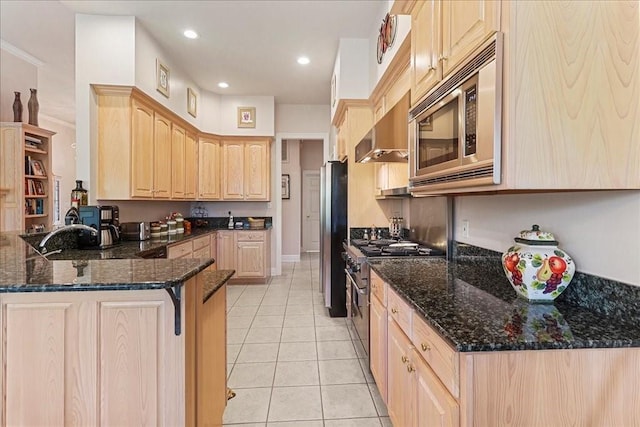 kitchen with light brown cabinets, light tile patterned flooring, kitchen peninsula, stainless steel appliances, and dark stone counters