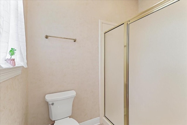 bathroom featuring toilet and a shower with shower door