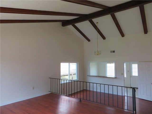 spare room featuring a wealth of natural light, dark hardwood / wood-style floors, and a chandelier