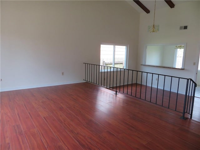 spare room featuring ceiling fan with notable chandelier, beamed ceiling, wood-type flooring, and high vaulted ceiling