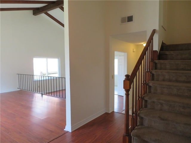 stairway featuring high vaulted ceiling, wood-type flooring, and beam ceiling