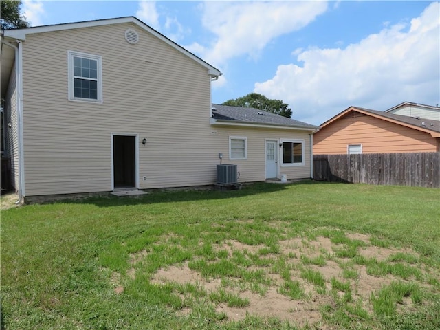 back of house with cooling unit and a lawn