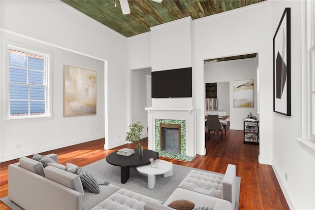 living room with ornamental molding, wood ceiling, ceiling fan, and dark wood-type flooring