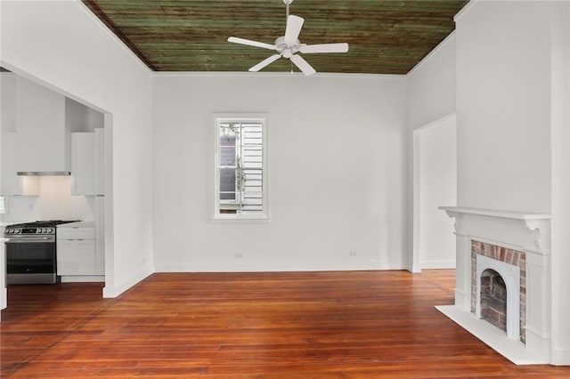 unfurnished living room featuring wood-type flooring, crown molding, ceiling fan, and a brick fireplace