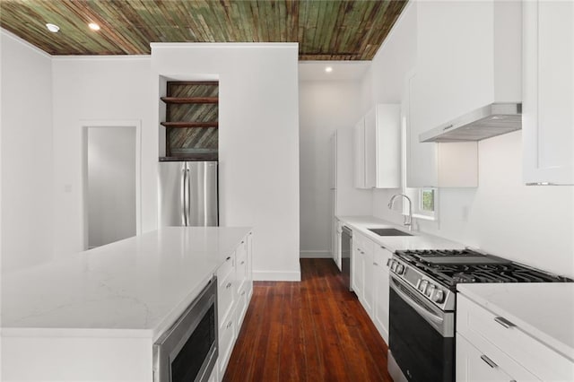 kitchen featuring white cabinets, wall chimney range hood, appliances with stainless steel finishes, dark hardwood / wood-style floors, and light stone countertops