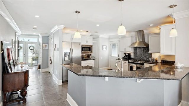 kitchen featuring wall chimney range hood, a healthy amount of sunlight, hanging light fixtures, and appliances with stainless steel finishes