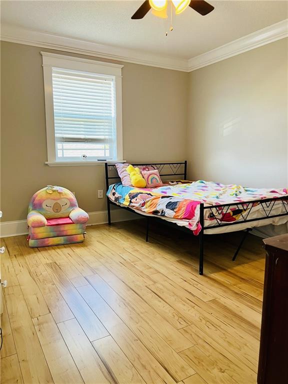 bedroom with ornamental molding, light wood-type flooring, and ceiling fan